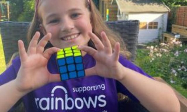 A smiling girl holding a Rubik's Cube