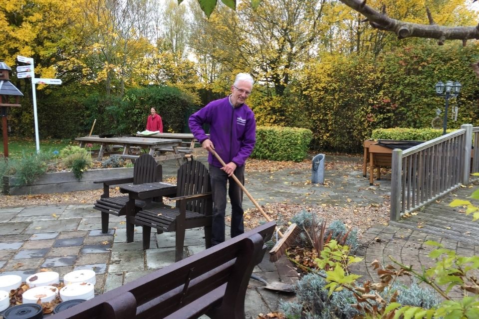 Male volunteer sweeping in the gardens