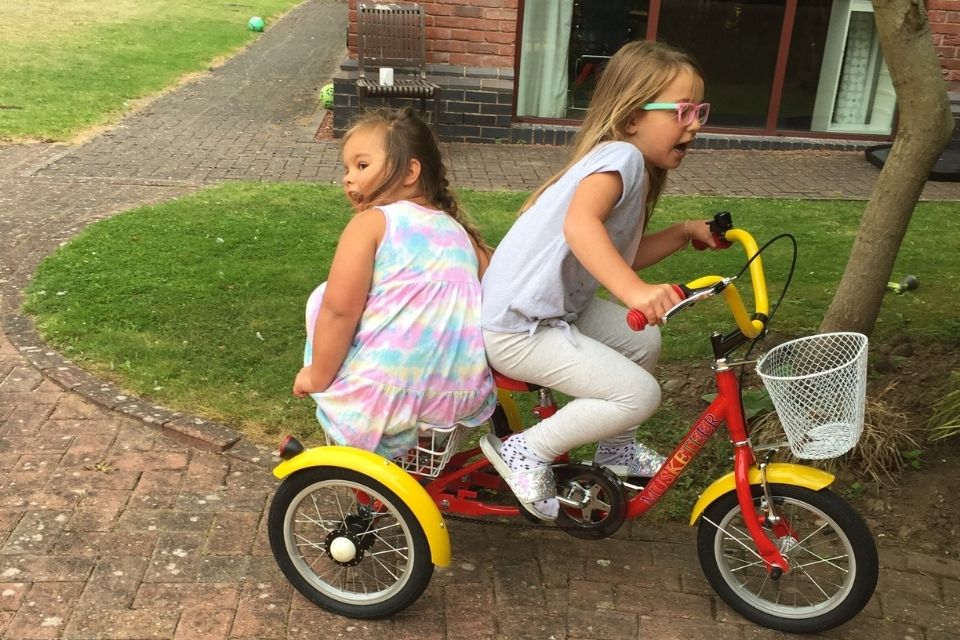 Two girls playing on a trike