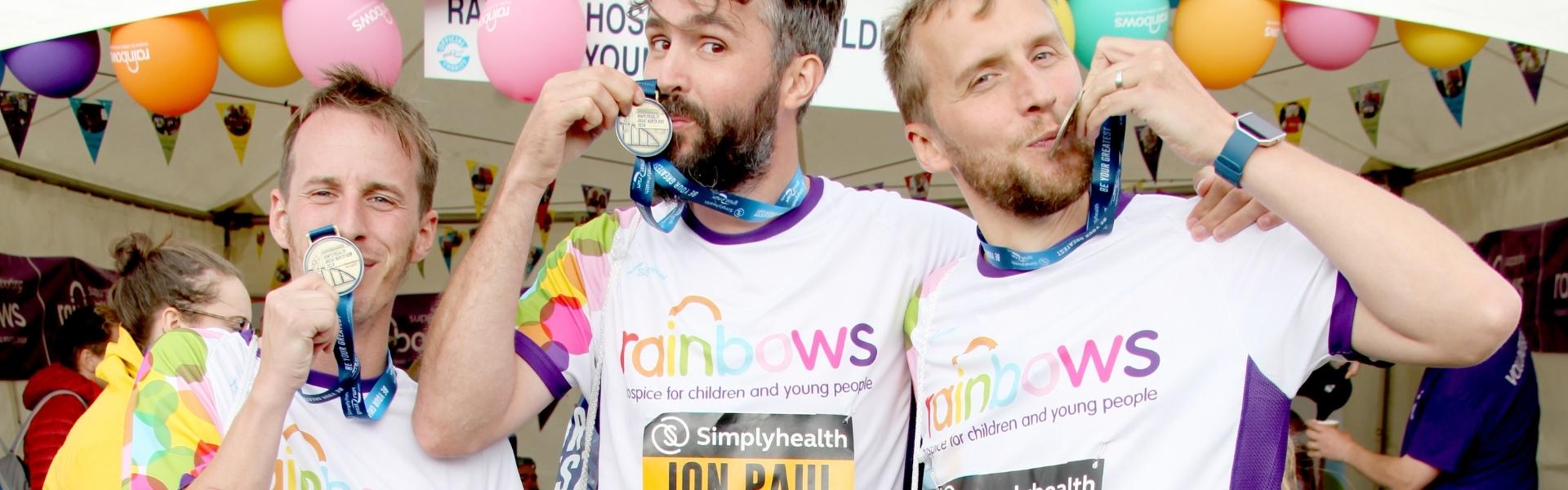 Three runners kissing their Great North Run medals