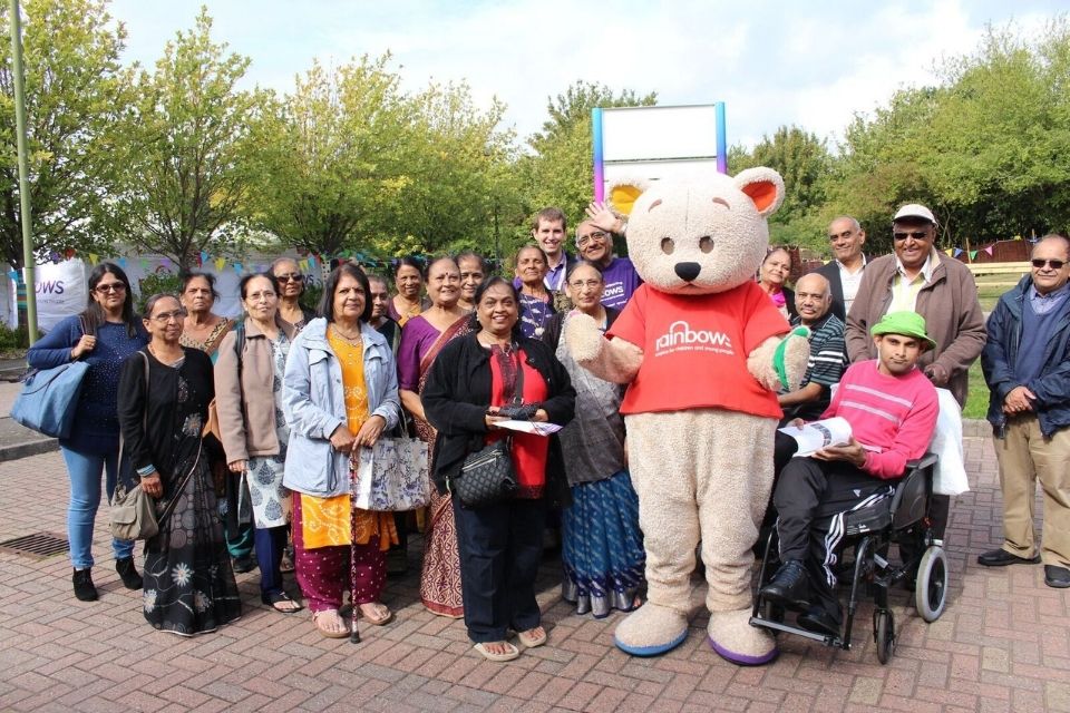 A group of people outside Rainbows Hospice with their mascot, Bow Bear