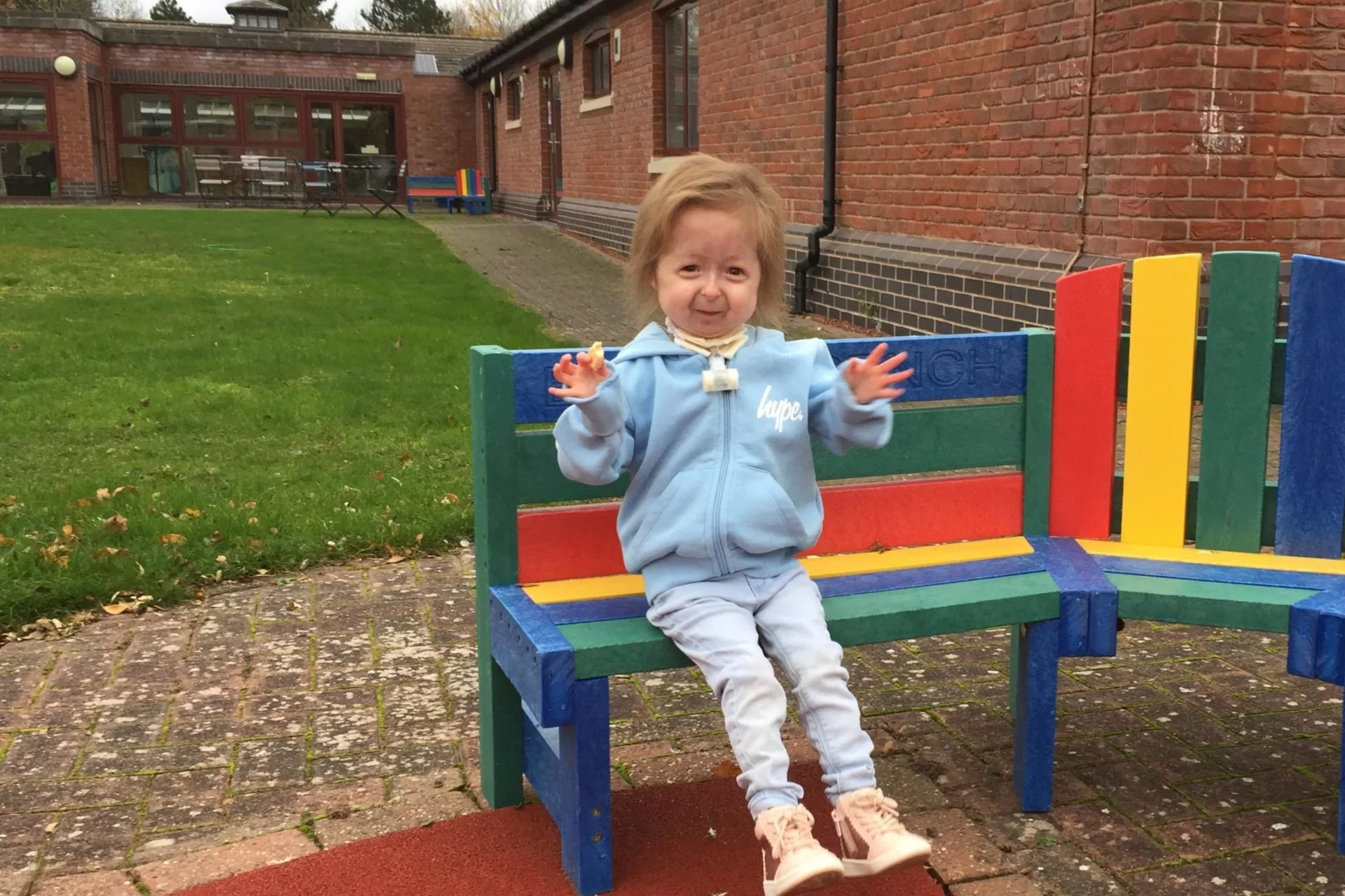 A young girl sat outside waving