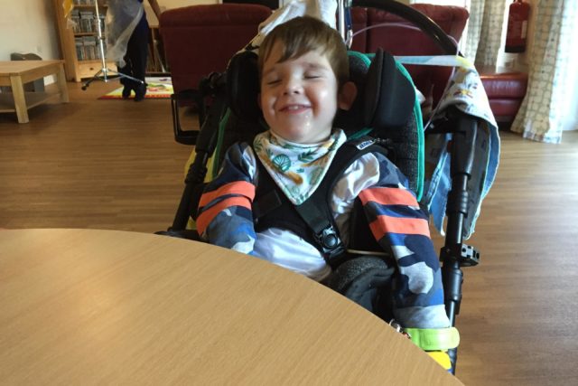 A young boy sat in his wheelchair smiling