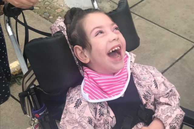 A young girl smiling in her wheelchair