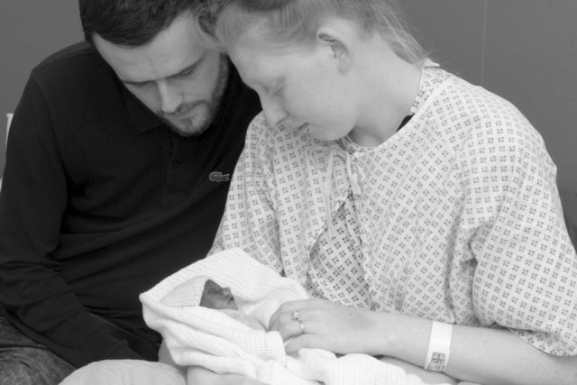 A mum and dad holding their baby