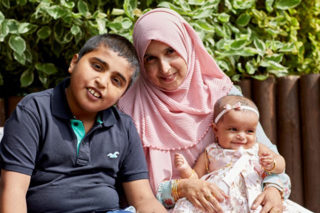 A young boy smiling with his mum and baby sister