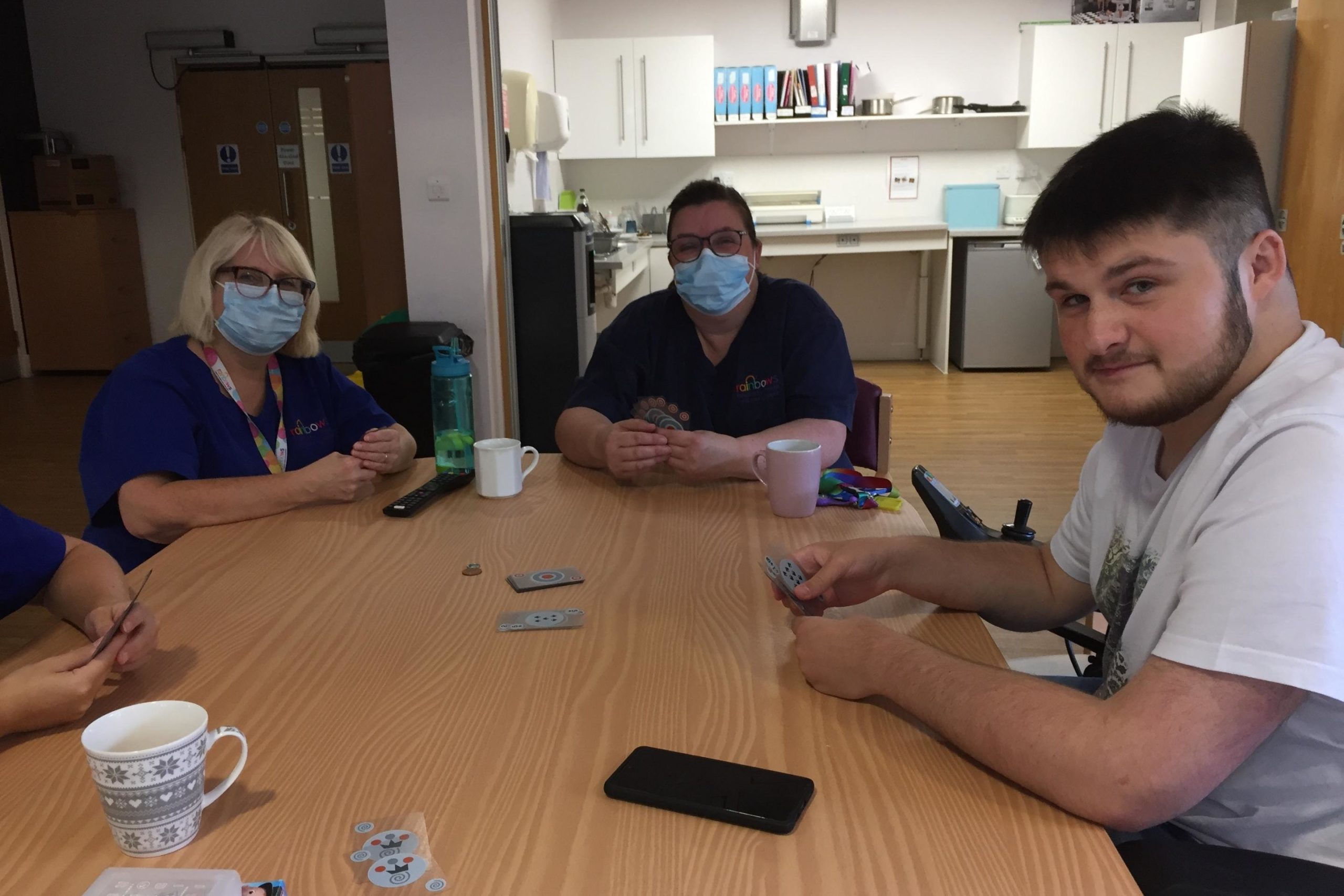 Care staff and a young man playing cards