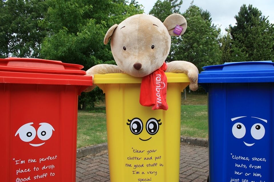 Red, yellow and blue wheelie bins with a teddy bear in