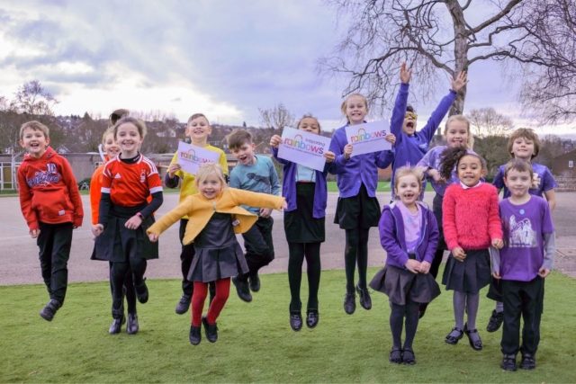 A group of school children smiling and jumping in the air